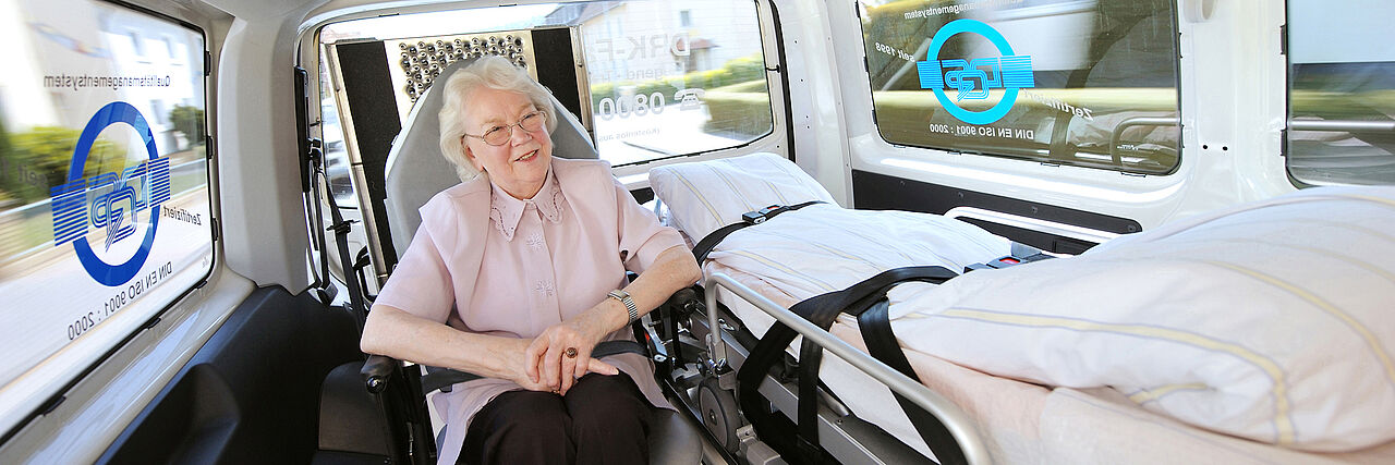 DRK Fahrdienst Hannover Portrait einer lächelnden Seniorin in einem Fahrzeug des DRK Krankentransportes.